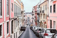 Wallpaper Line of Vehicles on Pink and Yellow Buildings