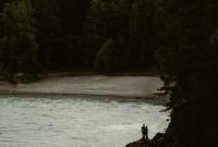 Wallpaper A Person Standing on a Rock in a Lake