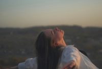 Wallpaper A Woman Standing in a Field with Her Arms Outstretched