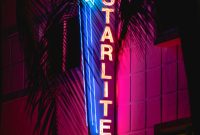 Wallpaper A Neon Sign is Lit Up on the Side of a Building
