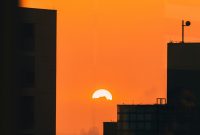 Wallpaper The Sun Setting Over a City with Tall Buildings