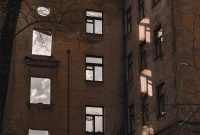 Wallpaper A Tall Building with Lots of Windows Next to a Tree