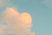 Wallpaper A Plane Flying Through a Cloudy Blue Sky